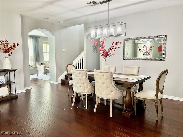 dining area with dark wood-type flooring and a notable chandelier