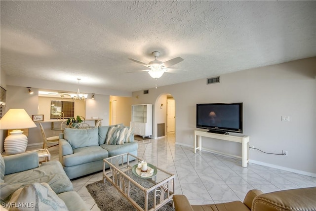 living room with ceiling fan with notable chandelier and a textured ceiling