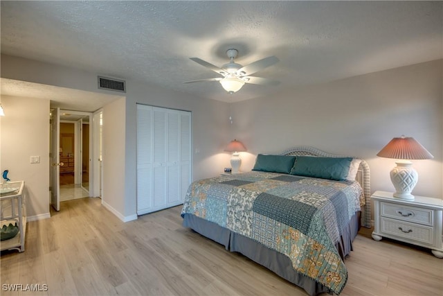 bedroom with ceiling fan, light hardwood / wood-style floors, a closet, and a textured ceiling