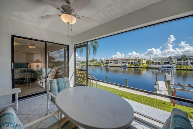 sunroom featuring ceiling fan and a water view