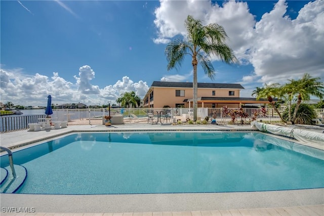 view of swimming pool featuring a patio and a water view