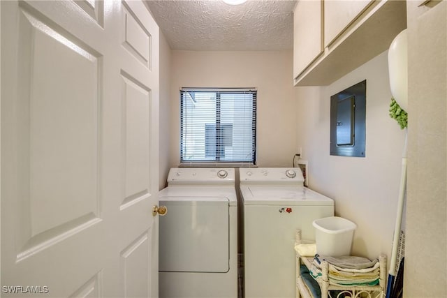 washroom with electric panel, cabinets, washing machine and dryer, and a textured ceiling