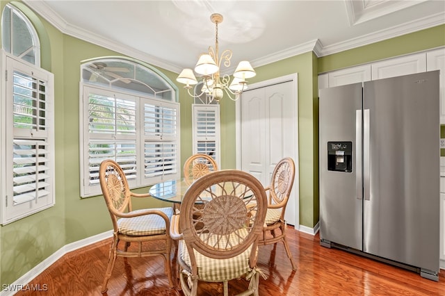 dining room with ornamental molding, hardwood / wood-style floors, and a notable chandelier