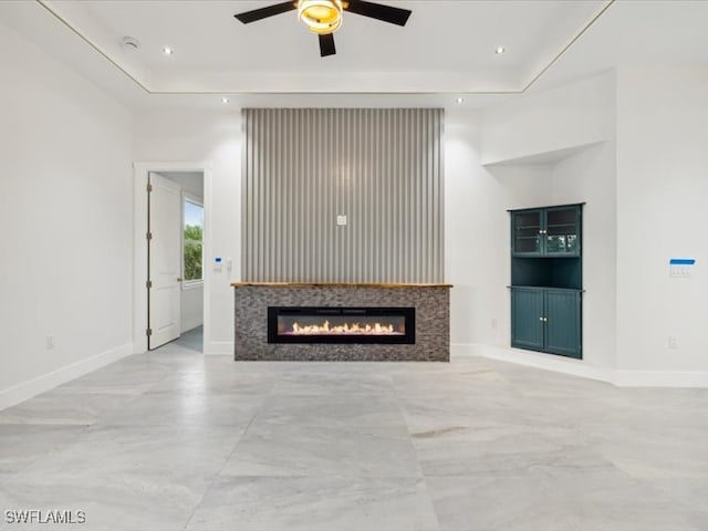 unfurnished living room with a tray ceiling and ceiling fan