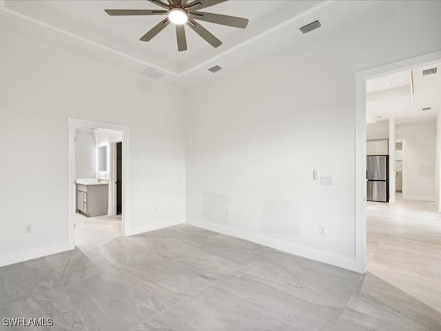 spare room featuring ceiling fan and a raised ceiling