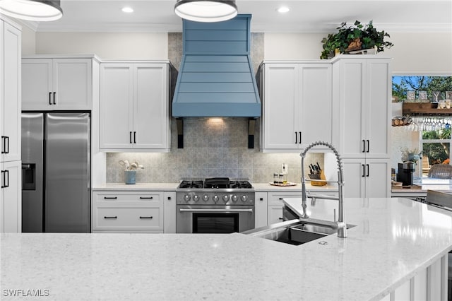 kitchen with light stone counters, white cabinets, sink, stainless steel appliances, and custom range hood