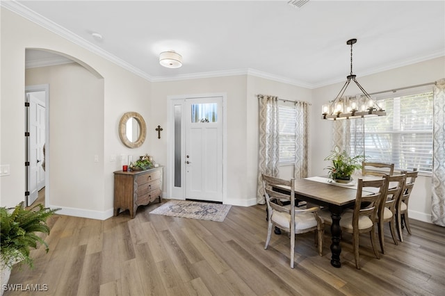 dining room with ornamental molding, hardwood / wood-style floors, and a chandelier