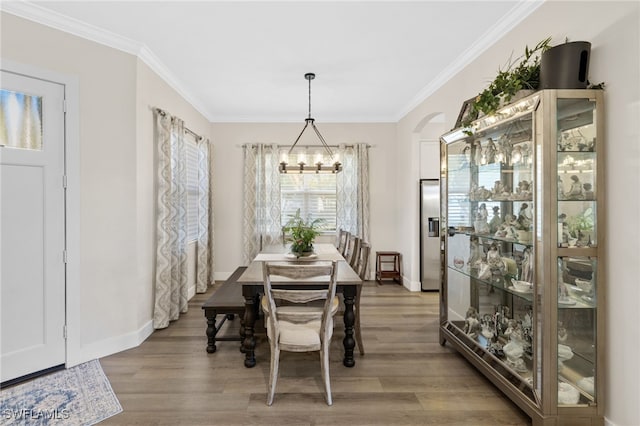 dining space with light hardwood / wood-style flooring, crown molding, and a chandelier