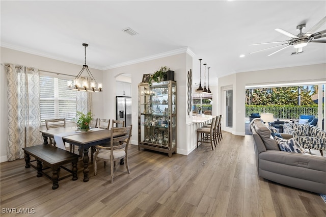 dining area featuring ornamental molding, ceiling fan with notable chandelier, and hardwood / wood-style floors