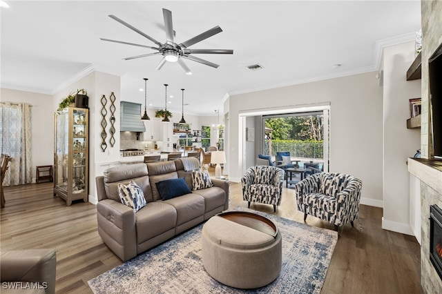 3684 Sudbury Ln, Bonita Springs, FL 34134 - living room featuring a glass covered fireplace, ceiling fan, wood finished floors, and crown molding