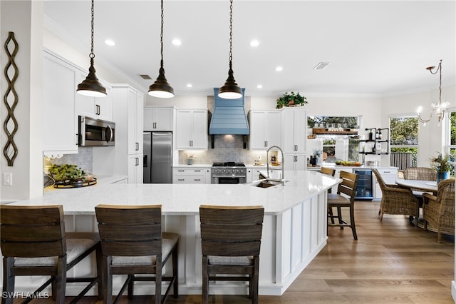 kitchen with sink, white cabinets, a kitchen bar, hanging light fixtures, and stainless steel appliances