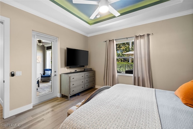 bedroom with ceiling fan, light hardwood / wood-style flooring, crown molding, and a tray ceiling