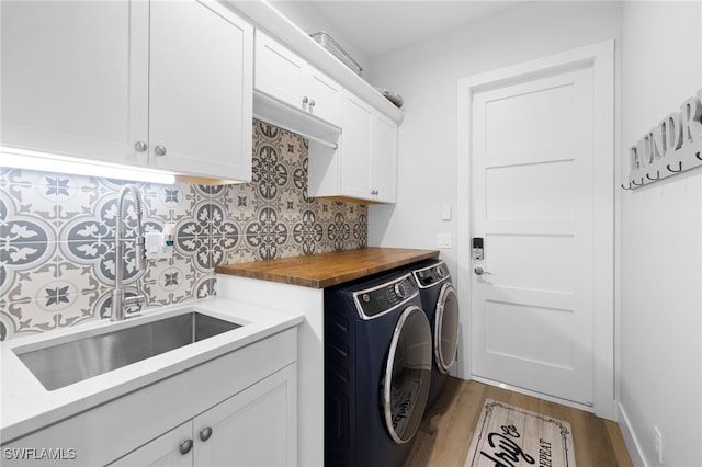 clothes washing area with cabinets, light wood-type flooring, sink, and washing machine and dryer