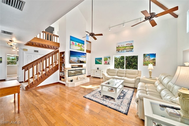 living room featuring light hardwood / wood-style floors, ceiling fan, and high vaulted ceiling