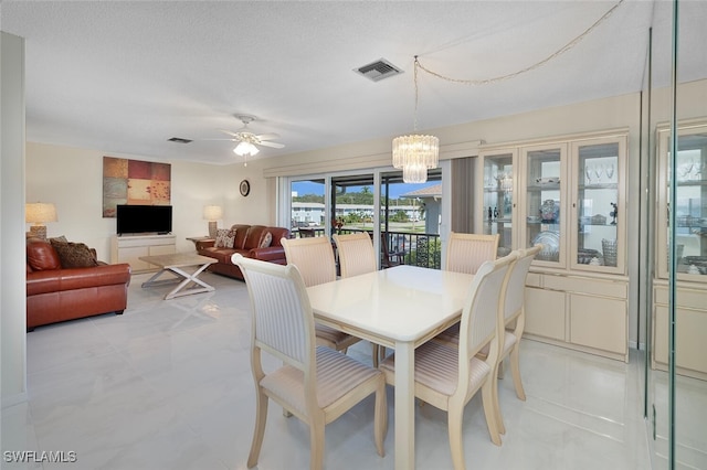 dining area with a textured ceiling and ceiling fan with notable chandelier