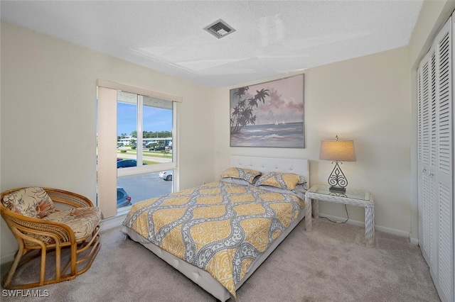 bedroom with light colored carpet, a textured ceiling, and a closet