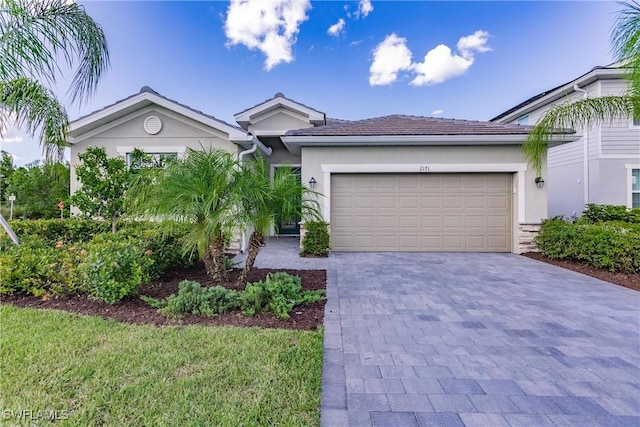 ranch-style house featuring decorative driveway, an attached garage, and stucco siding