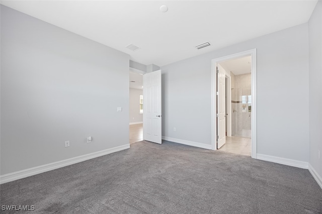 unfurnished bedroom featuring carpet floors and ensuite bathroom