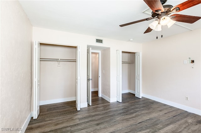 unfurnished bedroom with ceiling fan, multiple closets, and dark hardwood / wood-style flooring