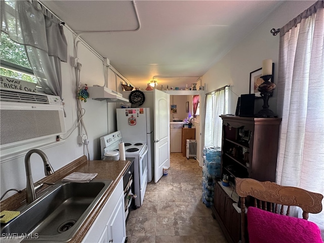 kitchen featuring white electric range, sink, radiator heating unit, and white cabinetry