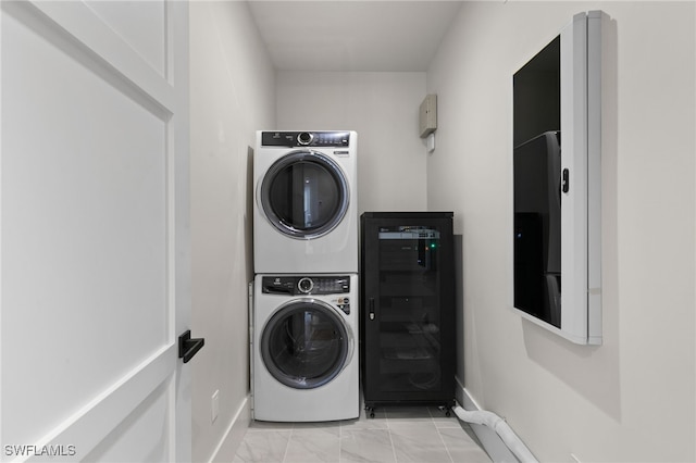 clothes washing area featuring beverage cooler, baseboards, laundry area, and stacked washer and clothes dryer