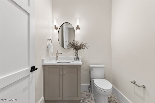 half bath with baseboards, vanity, and toilet