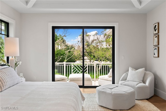 bedroom featuring baseboards, beamed ceiling, wood finished floors, and access to exterior