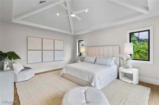 bedroom with ceiling fan, visible vents, wood finished floors, baseboards, and lofted ceiling
