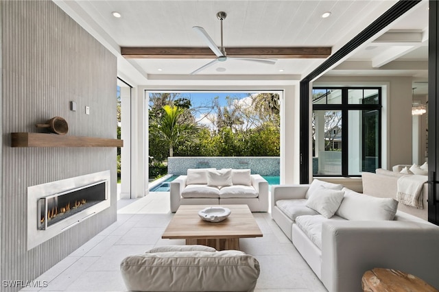 living room featuring beam ceiling, light tile patterned floors, a large fireplace, and ceiling fan