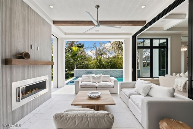 living area with recessed lighting, a ceiling fan, a warm lit fireplace, and beam ceiling