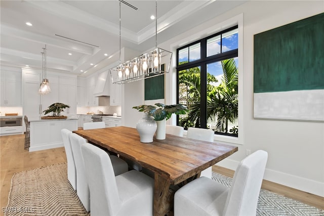 dining space with ornamental molding, light hardwood / wood-style flooring, and a raised ceiling