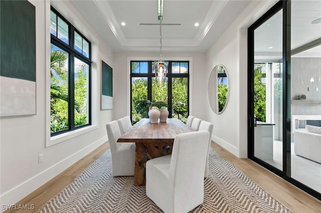 dining space with recessed lighting, a tray ceiling, baseboards, and light wood-style floors