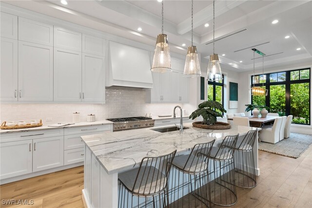 kitchen with light wood-type flooring, custom range hood, a sink, a tray ceiling, and recessed lighting