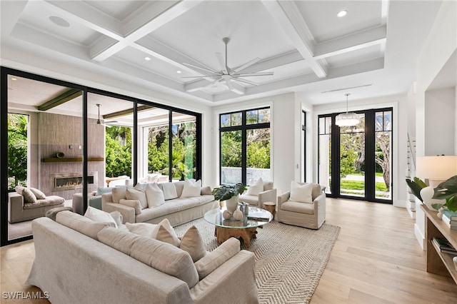 living room with ceiling fan, coffered ceiling, beamed ceiling, and light wood-type flooring