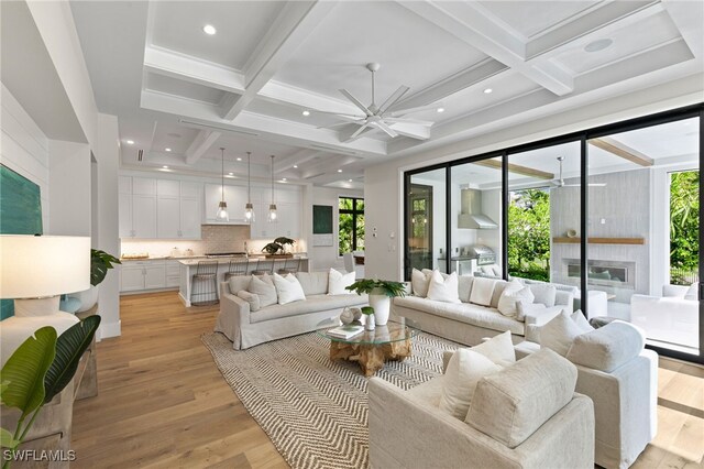 living room with a wealth of natural light, beamed ceiling, and light hardwood / wood-style flooring