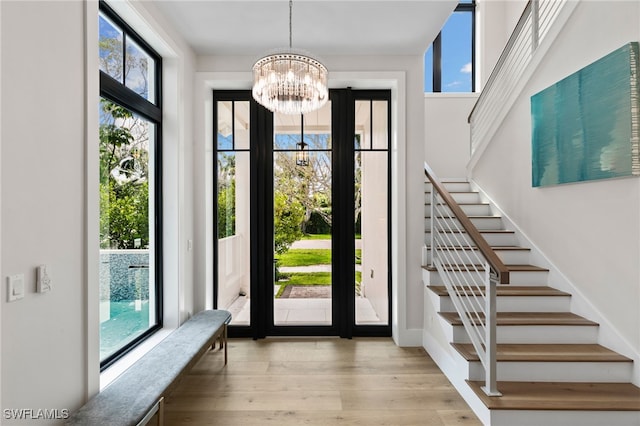 entrance foyer with stairs, wood finished floors, and a notable chandelier