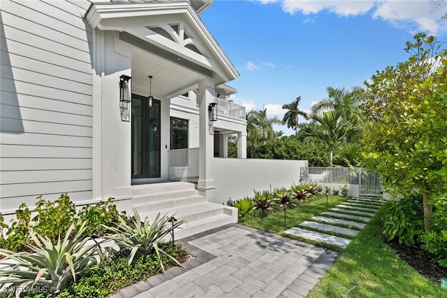 entrance to property with fence and a balcony