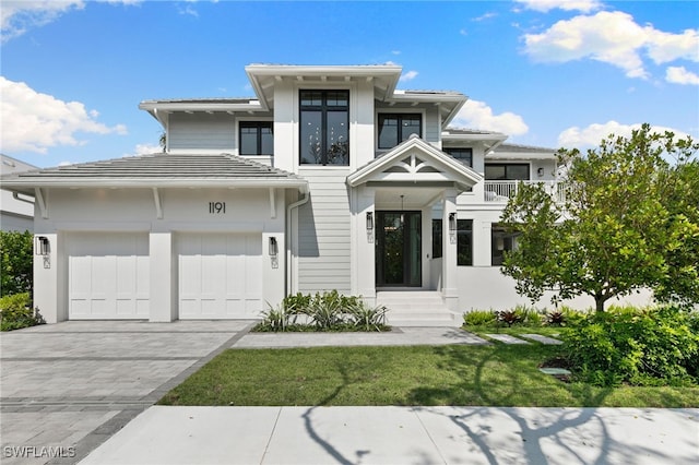 view of front of home featuring a front lawn, a garage, and a balcony