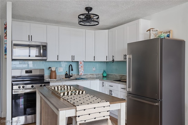 kitchen featuring white cabinets, appliances with stainless steel finishes, backsplash, and sink