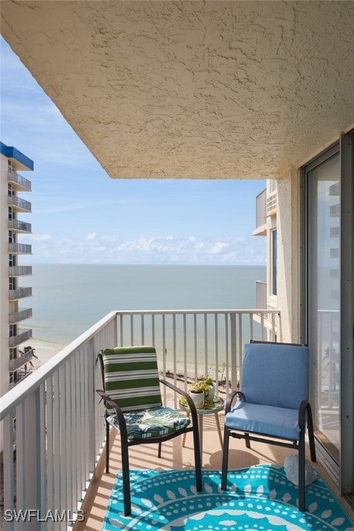 balcony featuring a view of the beach and a water view