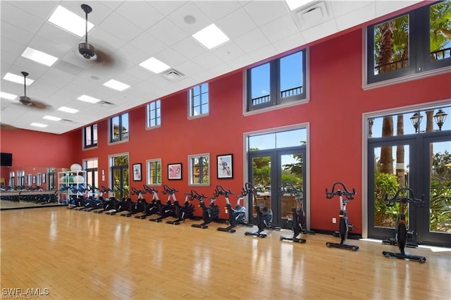 exercise room featuring wood-type flooring, french doors, a high ceiling, and ceiling fan