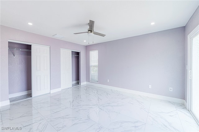 unfurnished bedroom with ceiling fan and two closets