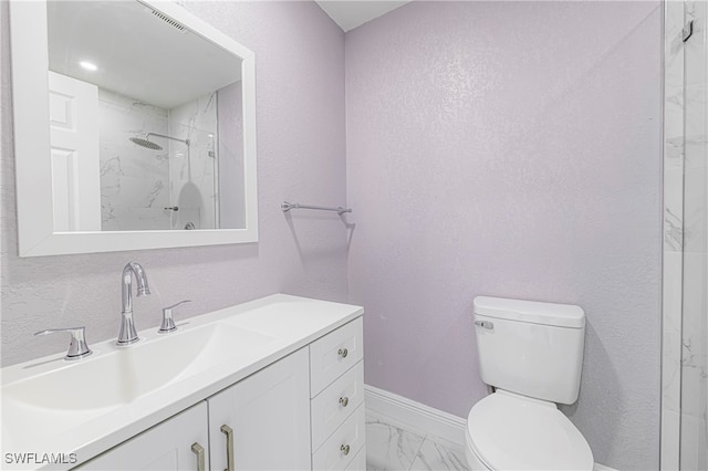 bathroom with vanity, tiled shower, and toilet