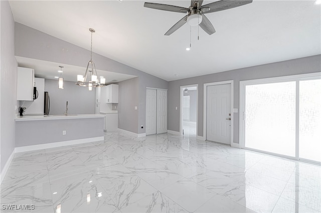 unfurnished living room with ceiling fan with notable chandelier and lofted ceiling