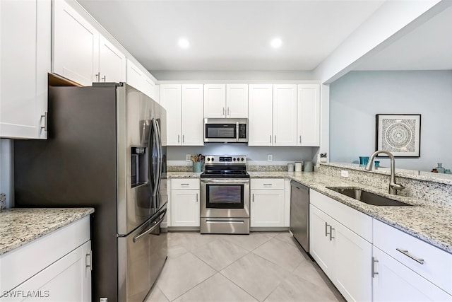 kitchen with light tile patterned floors, sink, white cabinetry, stainless steel appliances, and light stone countertops