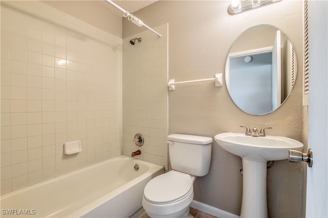 bathroom featuring tiled shower / bath combo and toilet