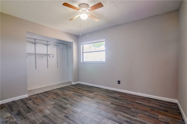 unfurnished bedroom featuring a closet, a textured ceiling, ceiling fan, and dark hardwood / wood-style flooring