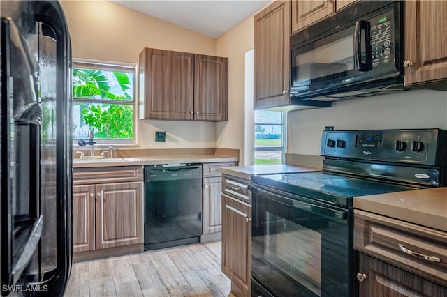 kitchen with light wood-type flooring, sink, lofted ceiling, and black appliances