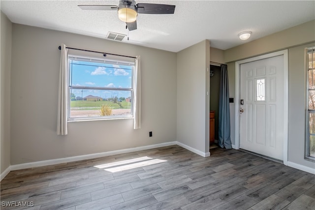 foyer with light hardwood / wood-style flooring, ceiling fan, and a textured ceiling