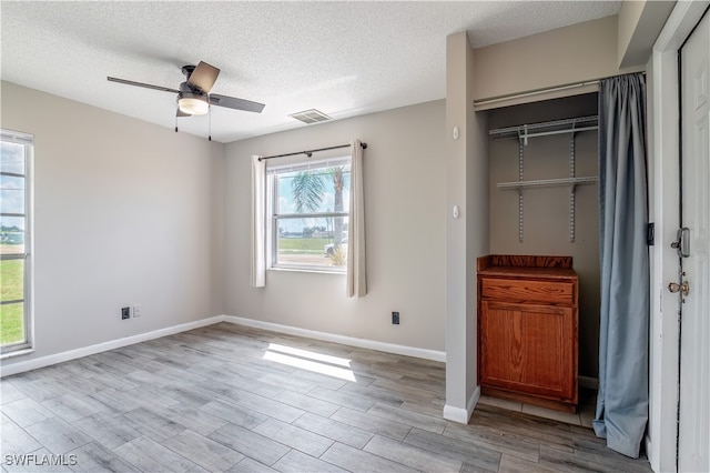 unfurnished bedroom with a textured ceiling, ceiling fan, a closet, and light hardwood / wood-style flooring